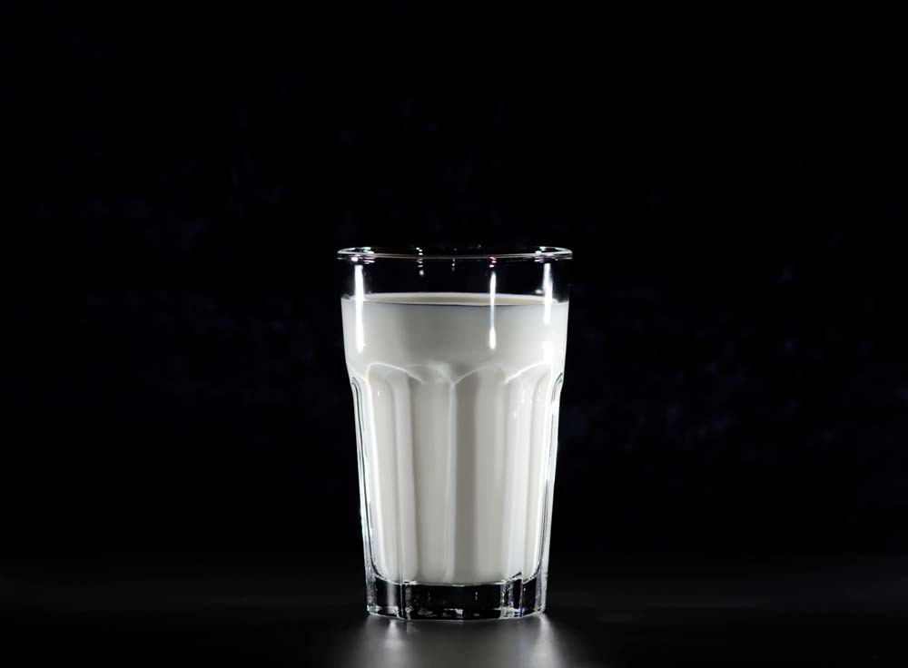 Image of a glass of calcium-filled milk against a black background