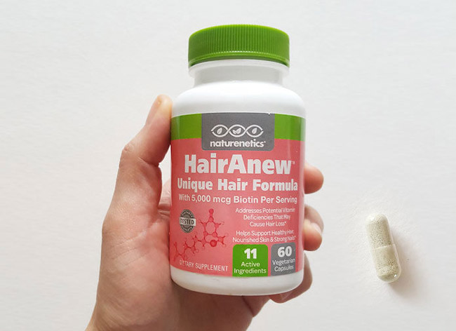 Image of a bottle of HairRenew and a capsule on a white table